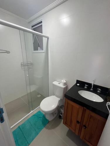 a bathroom with a toilet and a sink and a shower at Apto de ferias em Bertioga Maitinga in Bertioga