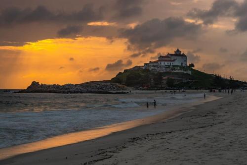 a beach with a building on top of a hill at Apartamento 2 quartos - Em frente a praia in Saquarema