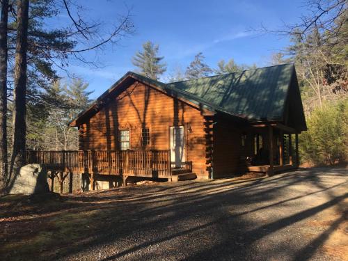 a log cabin in the woods with a porch at Three Daughters in Ferguson