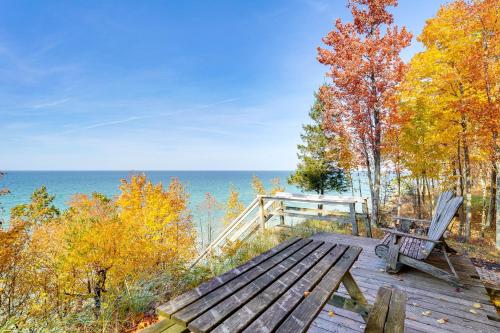 a wooden bench sitting on a wooden deck overlooking the water at Cottage with Private Beach and Fire Pit in Manistee! in Manistee