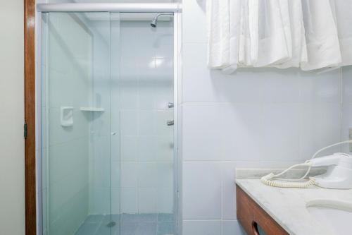 a glass shower in a bathroom with a sink at Tri Hotel Bento Gonçalves in Bento Gonçalves