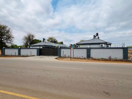 a building with sculptures on top of it next to a road at Nsuku Guest House in Phalaborwa