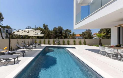 a swimming pool with chairs and an umbrella next to a building at Villa Meta in Petrcane