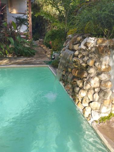 a waterfall in a pool with a rock wall at ECOVILLA CORAL GARDEN in Baoruco