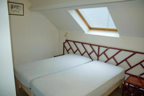 a bedroom with a white bed with a skylight at Résidence Durbuy in Durbuy