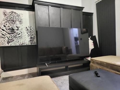 a living room with a television with a picture of a leopard at 30mins from Alton Towers - Panama Apartments Lodge in Stoke on Trent