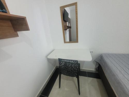 a small room with a white desk and a bed at Hospedaria São Benedito in Guararema