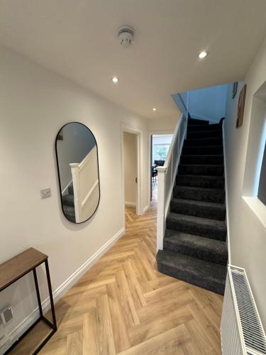 a hallway with a staircase with a mirror and a stair tread at 6 bedroom house in Orpington in Farnborough