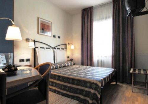 Habitación de hotel con cama, mesa y ventana en Hotel Alexander, en Fiorano Modenese