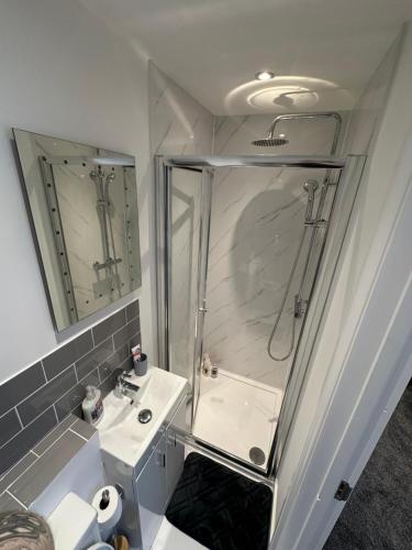 a white bathroom with a shower and a sink at 6 bedroom house in Orpington in Farnborough
