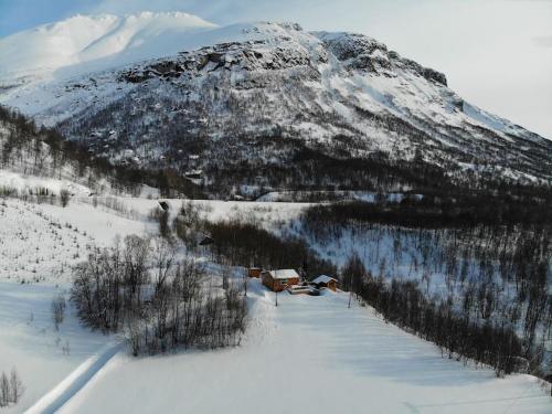 a snow covered mountain with a house in the foreground at Arctic Aurora View in Ytre Tomasjord