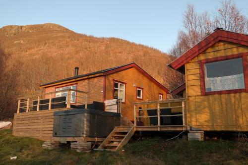 a wooden house with a hill in the background at Arctic Aurora View in Ytre Tomasjord