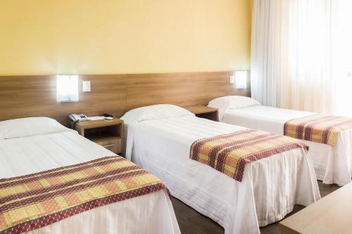 a hotel room with three beds in a room at Tri Hotel Bento Gonçalves in Bento Gonçalves
