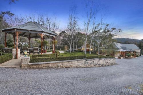 a gazebo with a stone wall in a park at Heart of a lion in Monbulk