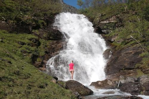 a woman standing in front of a waterfall at Arctic Aurora View in Ytre Tomasjord