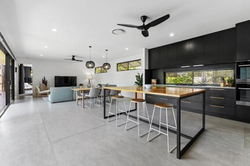 a kitchen with black cabinets and a island with bar stools at Stylish Home near Noosa & Peregian, walk to Beach in Marcus Beach