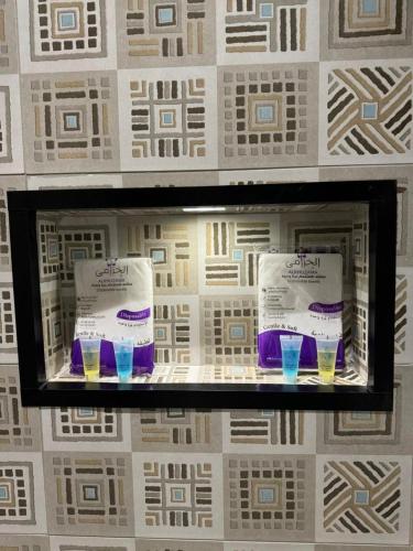 a display case with two bottles and glasses on a wall at شقة دار المنى الفندقية in Al Madinah