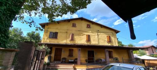 a yellow house with red windows on a street at Azienda agrituristica La Borgaccia in Baiso
