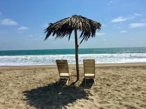 two chairs under an umbrella on the beach at Nativo Lodge Cabaña in Playas