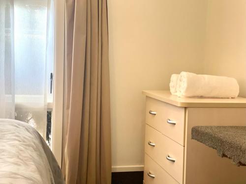 a bedroom with a bed and a dresser with a window at Ashleigh Court Motel-Christchurch Hagley Park in Christchurch