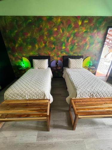 two beds in a room with a painting on the wall at Parti Gras Hotel & Villas en Playa Potrero in Potrero