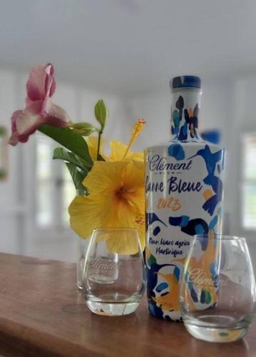 a bottle of water and a vase with flowers in it at Haut de villa 1chambre climatisée à 3min de l'habitation Clément in Le François