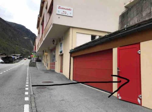 a garage with a red door on the side of a building at Chalet Julia mit Sauna in Eisten