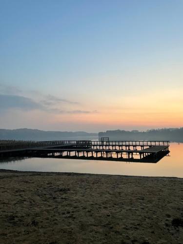 a pier on the water with the sunset in the background at Przystanek Zatoka in Olsztyn