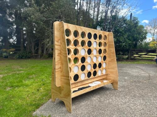 a large wooden four game board sitting in a park at Kauri Lodge in Taupaki