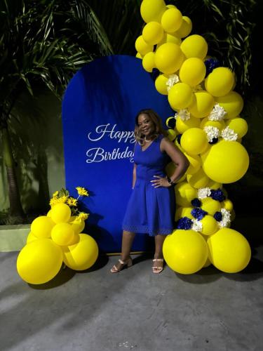 a woman standing in front of a wall of yellow balloons at Eve's Rockaway Villa in Alligator Pond Village