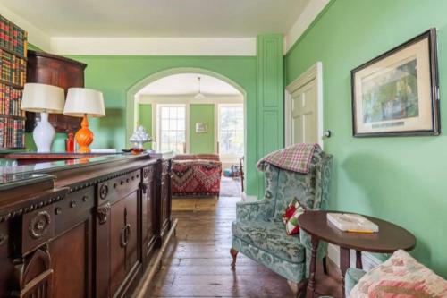 a kitchen with green walls and a table and a chair at Amazing Dockyard Historical Georgian House in Kent