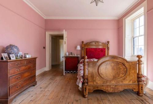 a bedroom with a wooden bed and pink walls at Amazing Dockyard Historical Georgian House in Kent