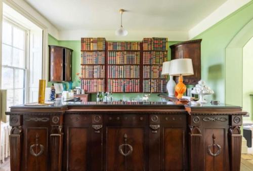 a library with a wooden desk with a lamp on it at Amazing Dockyard Historical Georgian House in Kent