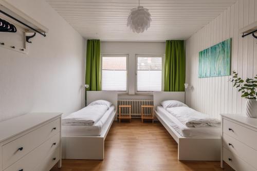 2 camas en una habitación con cortinas verdes en Centrally located 2-room apartment, en Hannover