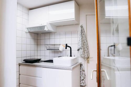 - une cuisine carrelée de blanc avec évier et cuisinière dans l'établissement Appartement cosy Carmes fibre & hyper centre, à Toulouse