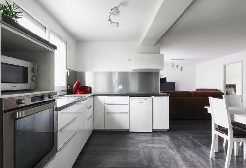 a kitchen with white cabinets and a microwave at Appartement de 70 m2 dans maison comptenporaine in Charnècles