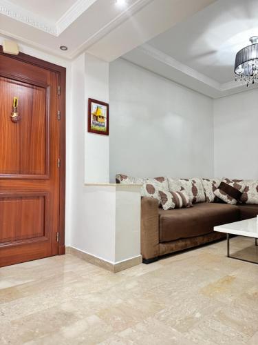 a living room with a couch and a wooden door at SUITOUISS - Agdal 3 - Appartement à 2 minutes de la gare de train TGV Rabat in Rabat