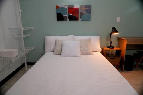 a bed with white sheets and pillows in a room at Ideal para trabajar y descansar in Cali