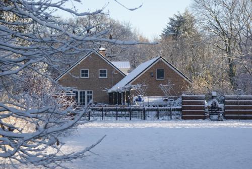 a house covered in snow in front of a fence at B&B Van Hunebed Naar Jullie Bed in Schoonoord