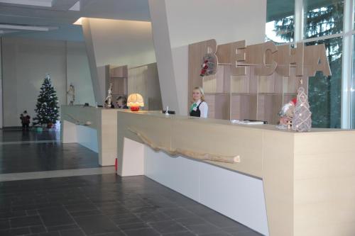 a woman standing at a counter in a lobby with a christmas tree at Hotel Vesna in Truskavets
