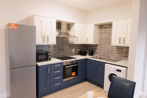 een keuken met blauwe kasten en een witte koelkast bij River Walk Apartments in Derry Londonderry