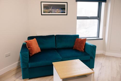 een woonkamer met een blauwe bank en een tafel bij River Walk Apartments in Derry Londonderry
