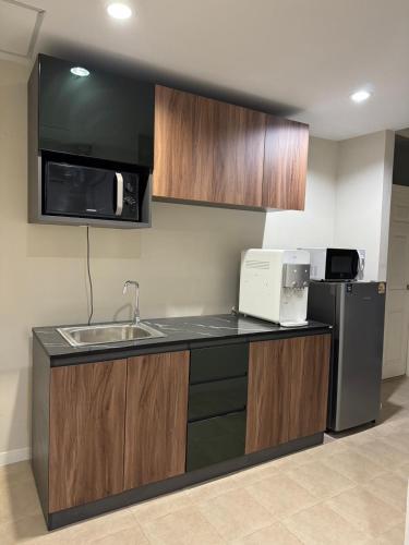 a kitchen with a sink and a microwave at EM HOME Sukhumvit Bangkok - near Terminal 21, EM District Malls, BTS and MRT Lines in Bangkok