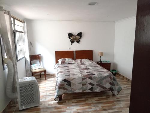 a bedroom with a bed with a butterfly on the wall at Linda casa vacacional Andy-Santiago de Cali in Cali