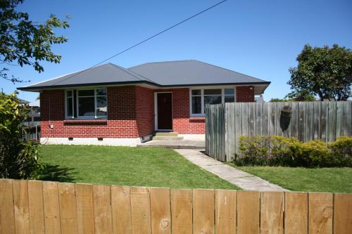 a red brick house behind a wooden fence at Weka Retreat in Ashburton