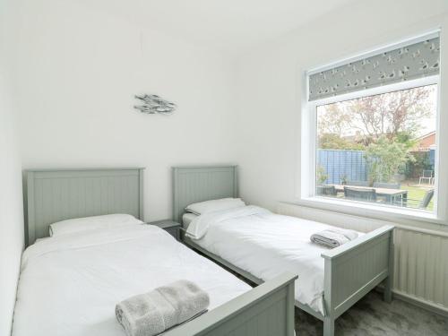 two beds in a room with a window at The Seaside Retreat in Mablethorpe