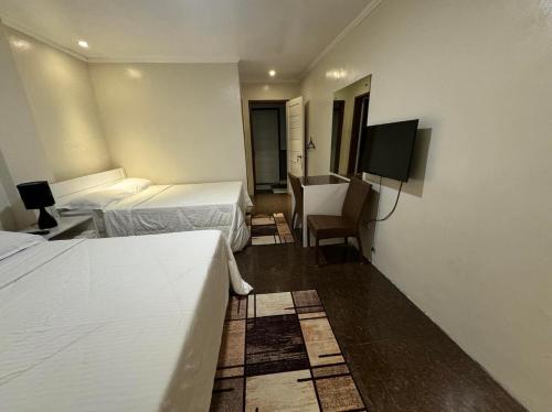 a hotel room with two beds and a flat screen tv at Phuenics de galera in Puerto Galera