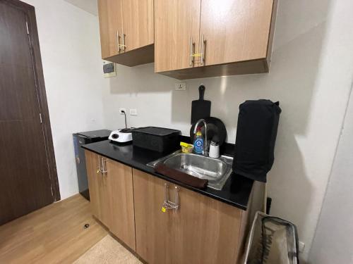 eine kleine Küche mit einem Waschbecken und Holzschränken in der Unterkunft Condo unit in The Loop Limketkai CDO in Cagayan de Oro