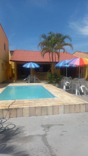 a swimming pool with chairs and umbrellas next to a building at Pousada Amarela Beach in Itanhaém