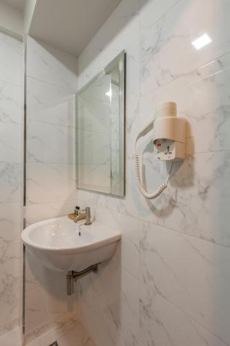 a white bathroom with a sink and a mirror at RCN Court & Inn in Chiang Mai